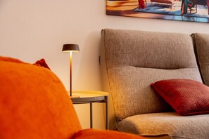 Una habitación con sofá, lámpara y un cuadro en la pared.