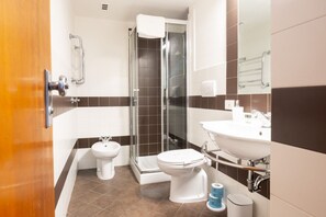 A modern bathroom with a shower, two toilets, a sink, and a mirror. - Joyful Lungarno Apartment (Florence)