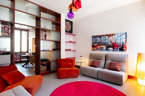 A modern living room with a sofa, armchairs, and a red rug. There is a dining area with chairs and a table, and a kitchen in the background. - Joyful Lungarno Apartment (Florence)