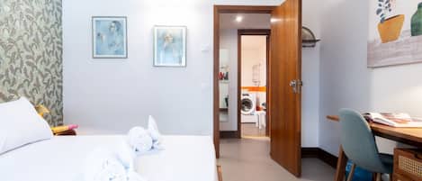 Habitación de hotel con cama, escritorio y una silla. Hay una puerta que da a un lavadero.