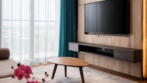 A modern living room with a flat-screen TV, a sofa, a coffee table, and a potted orchid.