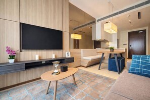 Un salon moderne doté d’un téléviseur à écran plat, d’une table basse ronde, d’un canapé et d’un coin repas avec une table et des chaises.