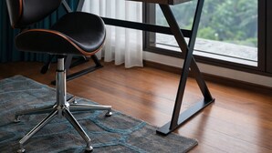 A modern office chair, a desk with a laptop, and a view through a large window.