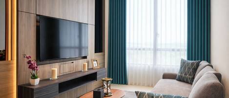 Una sala de estar moderna con un televisor de pantalla plana, un sofá, una mesa de centro y una planta en maceta.