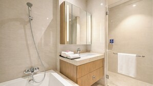 A modern bathroom with a bathtub, a shower, a vanity with a mirror, and a towel rack.