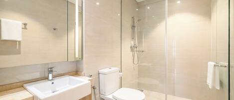 A modern bathroom with a glass-enclosed shower, a white sink, and a toilet.