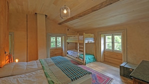 Un dormitorio de cabaña de madera con literas, una cama individual y un escritorio.