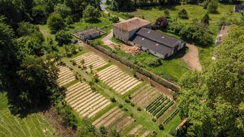 An aerial view of a farm with multiple crop fields, a farmhouse, and surrounding greenery.