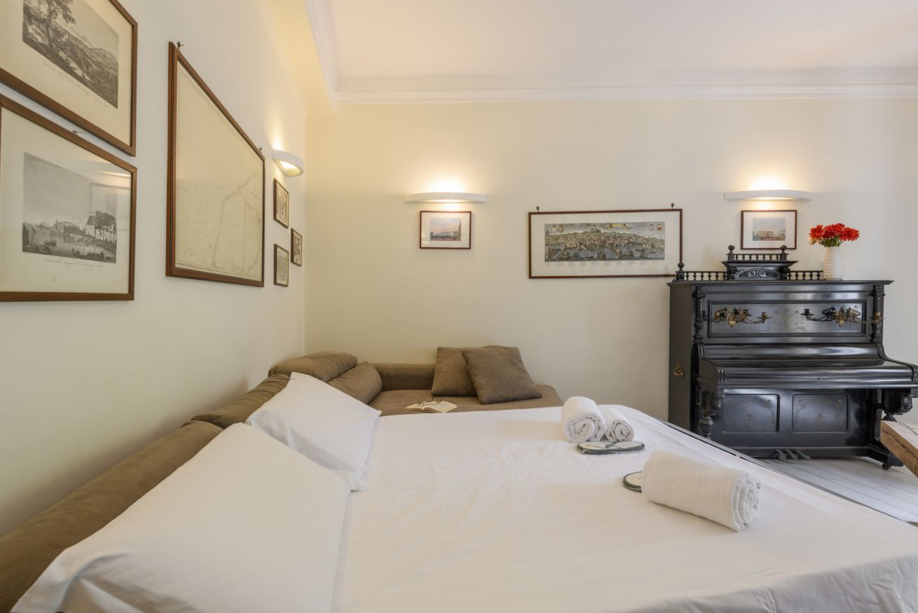 Una habitación de hotel con cama, sofá, piano y cuadros en la pared.