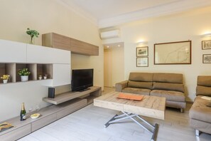 A modern living room with a flat-screen TV, a sofa, a coffee table, and built-in shelving with plants. - Tibaldi, 29 - Bright between Bocconi and Navigli (Milan)