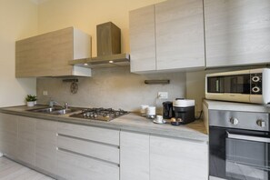 A modern kitchen with a gas stove, microwave, and oven, light wood cabinetry, and a stainless steel sink. - Tibaldi, 29 - Bright between Bocconi and Navigli (Milan)
