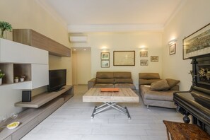 A living room with a TV, sofas, a coffee table, a piano, and wall-mounted artwork. - Tibaldi, 29 - Bright between Bocconi and Navigli (Milan)