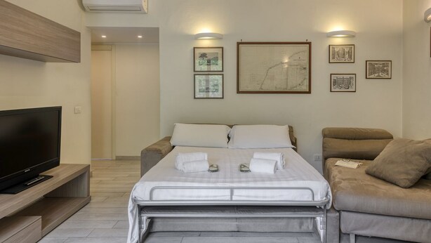 Habitació d'hotel moderna amb un llit, una televisió i obra d'art a les parets.