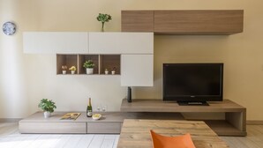 Un saló modern amb televisió de pantalla plana, prestatges integrats, una taula de centre i un sofà.