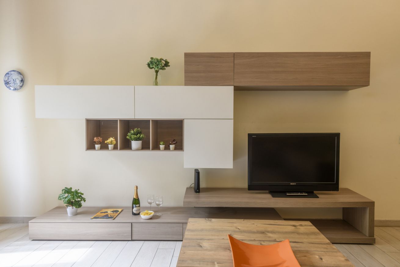 Een moderne woonkamer met een flatscreen televisie, inbouwplanken, een salontafel en een bank.