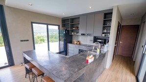 Een moderne keuken met een groot eiland, barkrukken en inbouwplanken.