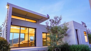 Een modern huis met grote ramen, een trap en een verzorgde tuin.