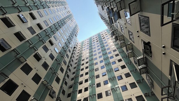 Ein Hochhaus mit mehreren Stockwerken, großen Fenstern und Klimaanlagen.