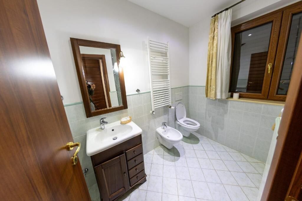 A bathroom with a sink, mirror, toilet, and towel rack.