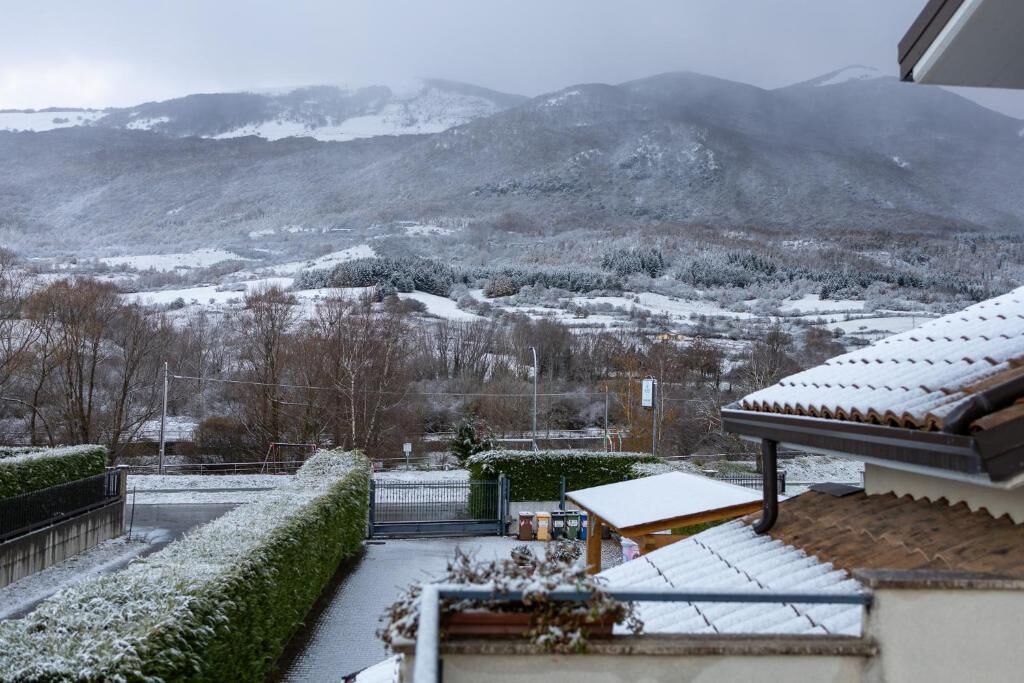 A snowy landscape with a building featuring a tiled roof and a small wooden structure.