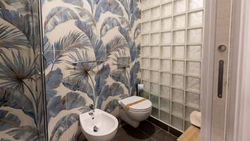 A bathroom with a shower, a bidet, and a toilet.