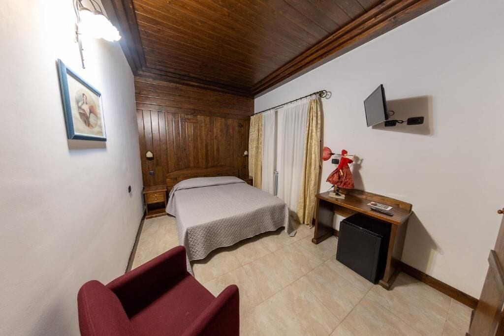 Un dormitorio con cama, escritorio, silla, televisor y un refrigerador pequeño.