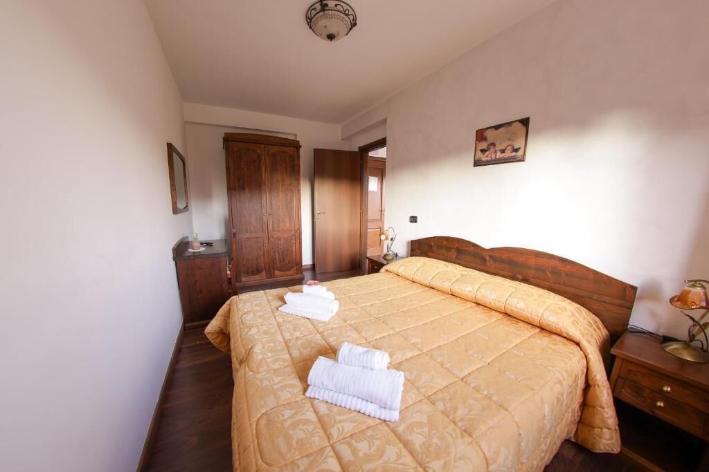Quarto com uma cama grande, guarda-roupa de madeira e um quadro na parede.