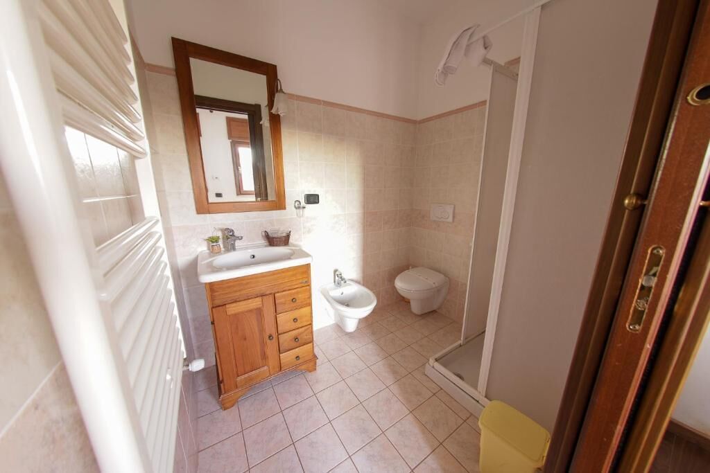 Un baño con tocador de madera, lavamanos, bidé, inodoro y ducha.