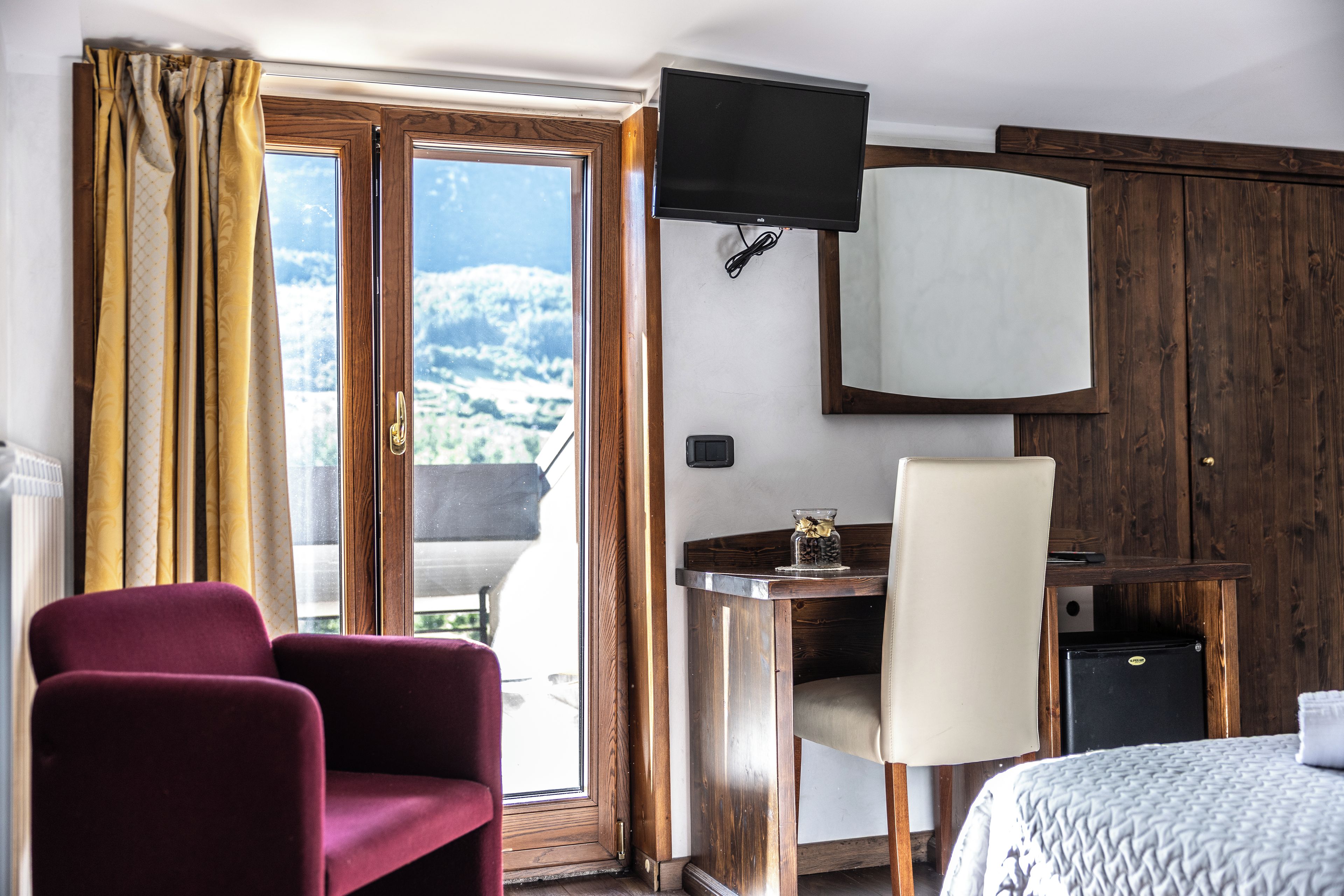 Una habitación de hotel con una cama, un escritorio, una silla, un televisor y vistas al exterior.