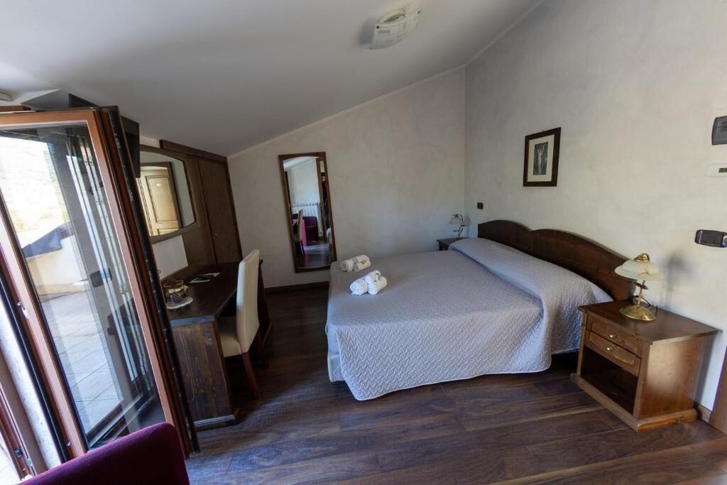 Une chambre à coucher comprenant un lit, un bureau, une chaise, une table de chevet avec une lampe et un miroir.