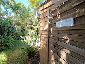 A wooden gate with a sign reading 'Cabane des tropiques' and lush tropical vegetation.