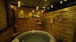Una habitación de madera con jacuzzi, luces cálidas y estantes en la pared con plantas.