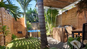 A patio area with a table and chairs, a grill, and a wooden fence. - Cabin 'La Cabane Tropicale' with Private Pool, Wi-Fi and Air Conditioning (Saint-Louis)