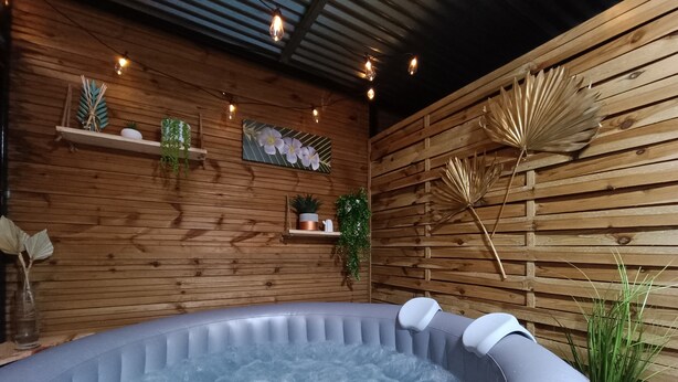 A hot tub in a wooden room with shelves and plants. - Cabin 'La Cabane Tropicale' with Private Pool, Wi-Fi and Air Conditioning (Saint-Louis)