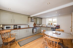 A kitchen with wooden cabinets, a microwave, a stove, and a dining table with chairs.