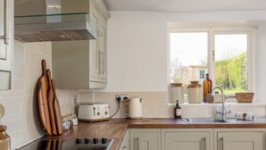 Una cocina con encimera de madera, estufa integrada, ventana con vistas y armarios de colores claros.