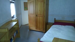 Une chambre à coucher avec un lit, une armoire en bois et une petite table.