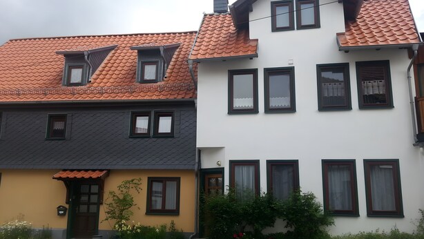 Une rangée de maisons à deux étages, caractérisées par des tuiles distinctives et de nombreuses fenêtres.