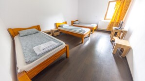 Quarto com três camas de madeira, uma mesa pequena e um radiador.