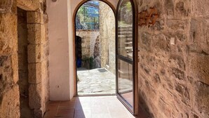 A stone-walled corridor with an arched doorway leading to an outdoor area.
