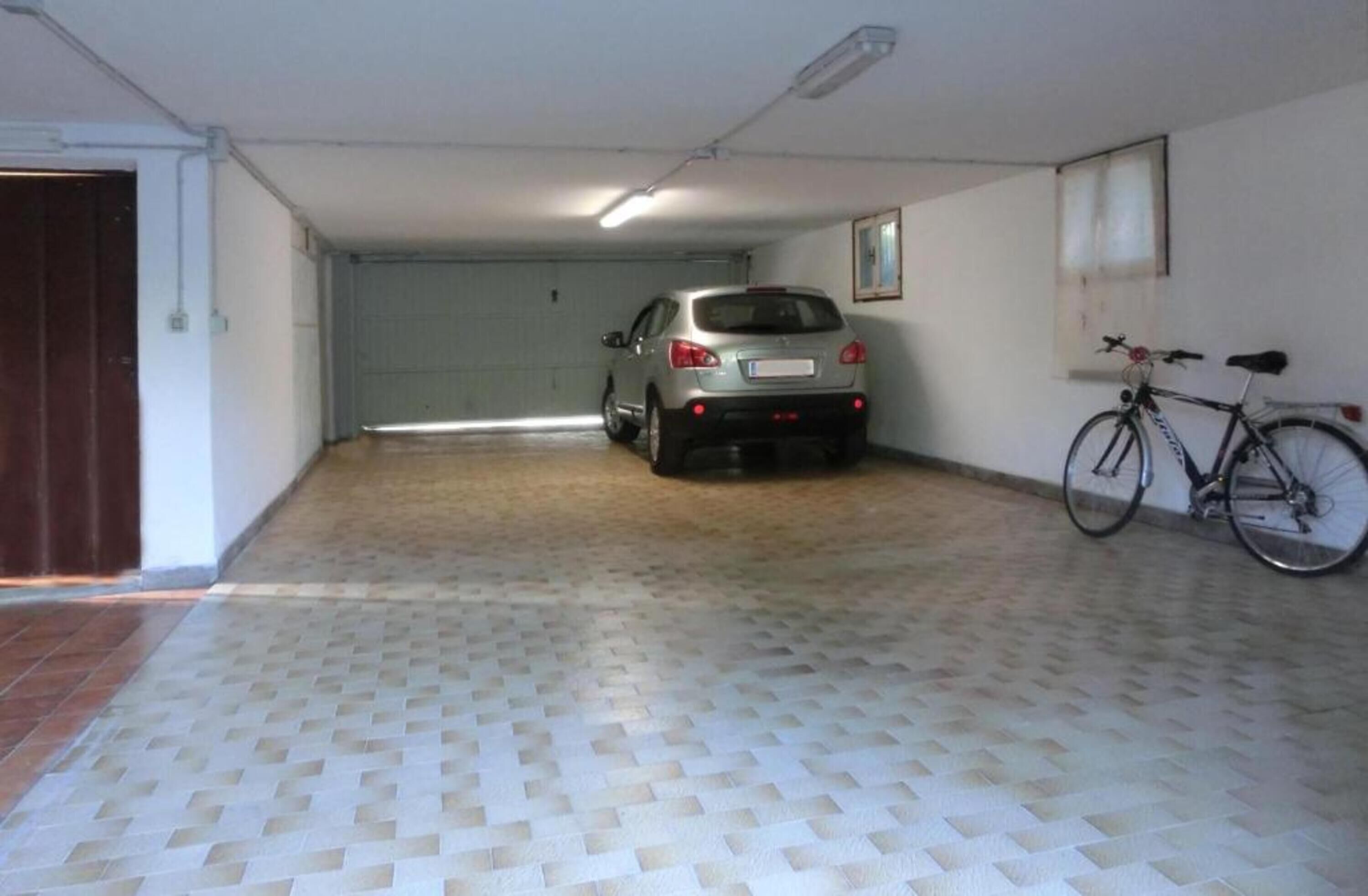 A parking garage with a car and a bicycle.