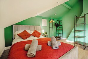 A bedroom with a bed, pillows, a red blanket, and rolled towels. - Velvet Residence Central Sheffield | Parking 12PPL (Sheffield)
