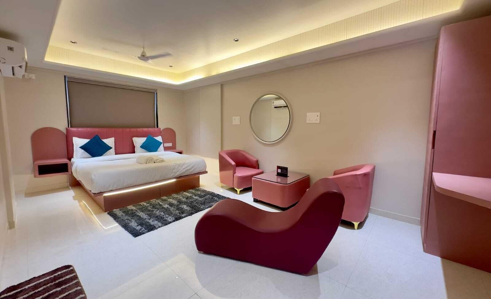 Un dormitorio moderno con cama, un espejo redondo, un escritorio y dos sillas.