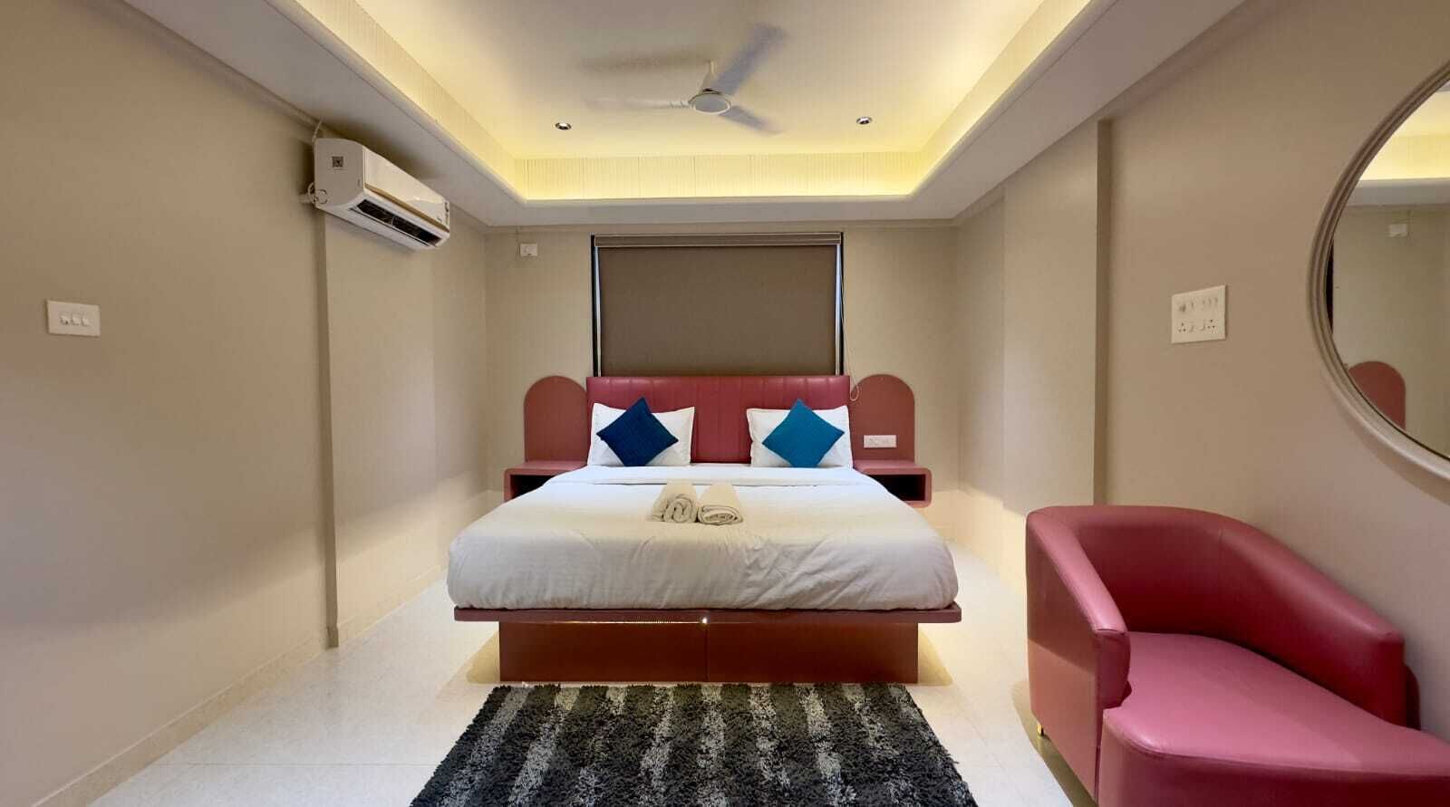Una camera da letto con un letto, una sedia rossa, una ventola a soffitto e un condizionatore d'aria.