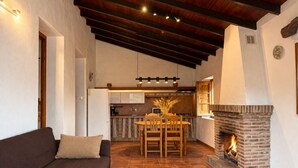 Ein gemütliches Wohnzimmer mit Kamin, Essbereich und einer Küche im Hintergrund.