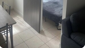 Una stanza con una porta scorrevole, un letto, una sedia e un tavolo.