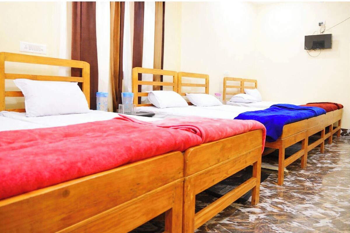 Habitación de hotel con cuatro camas de madera, cada una con un edredón de color diferente.