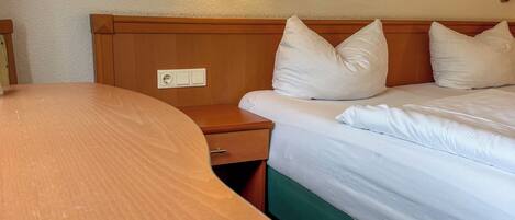 Una habitación de hotel con cama, mesita de noche, lámpara y un cuadro colgado en la pared.