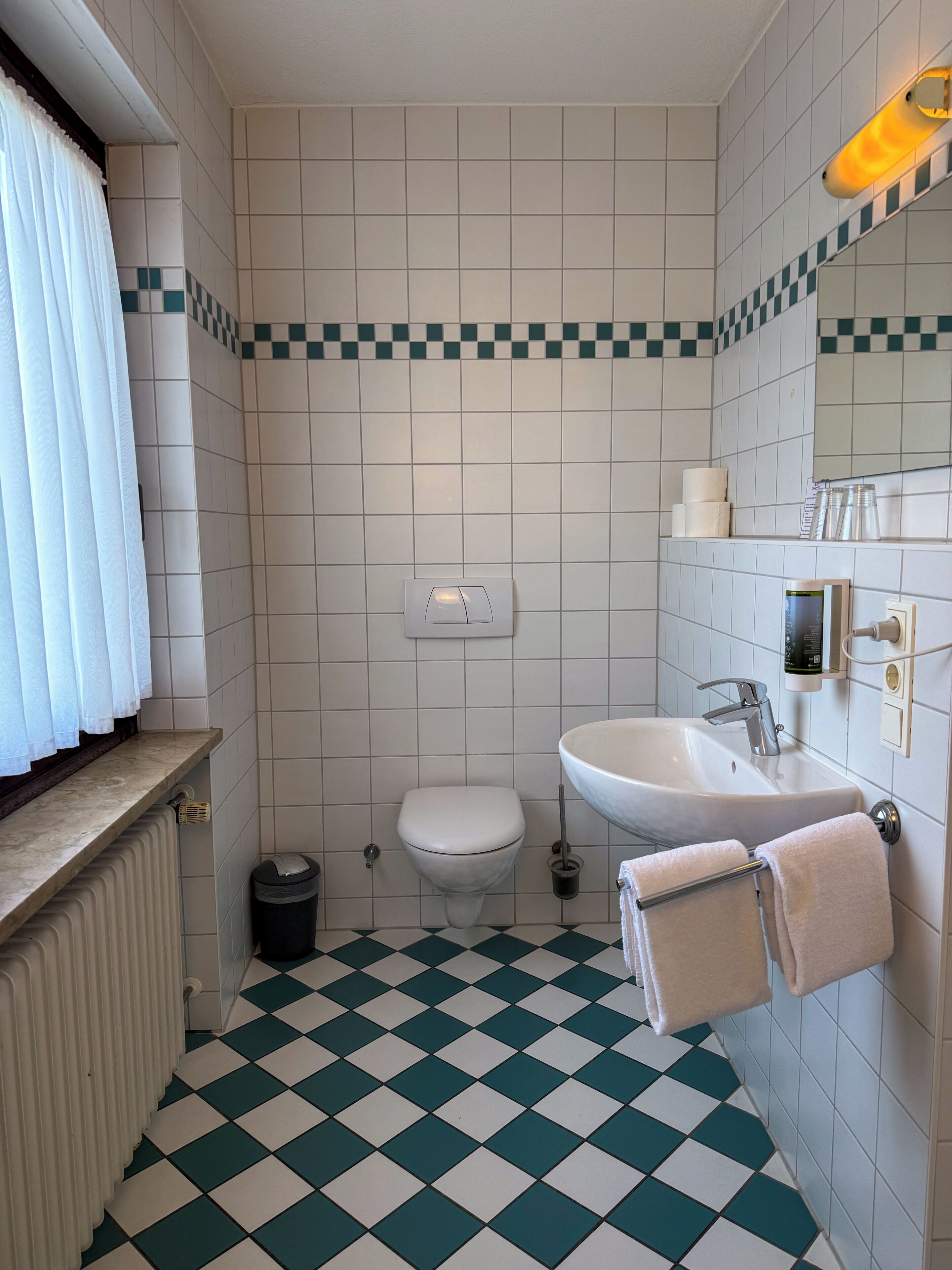 A bathroom with a toilet, sink, and radiator.