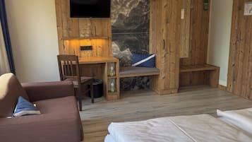A room with a bed, a sofa, a desk with a TV, and a wooden wardrobe.